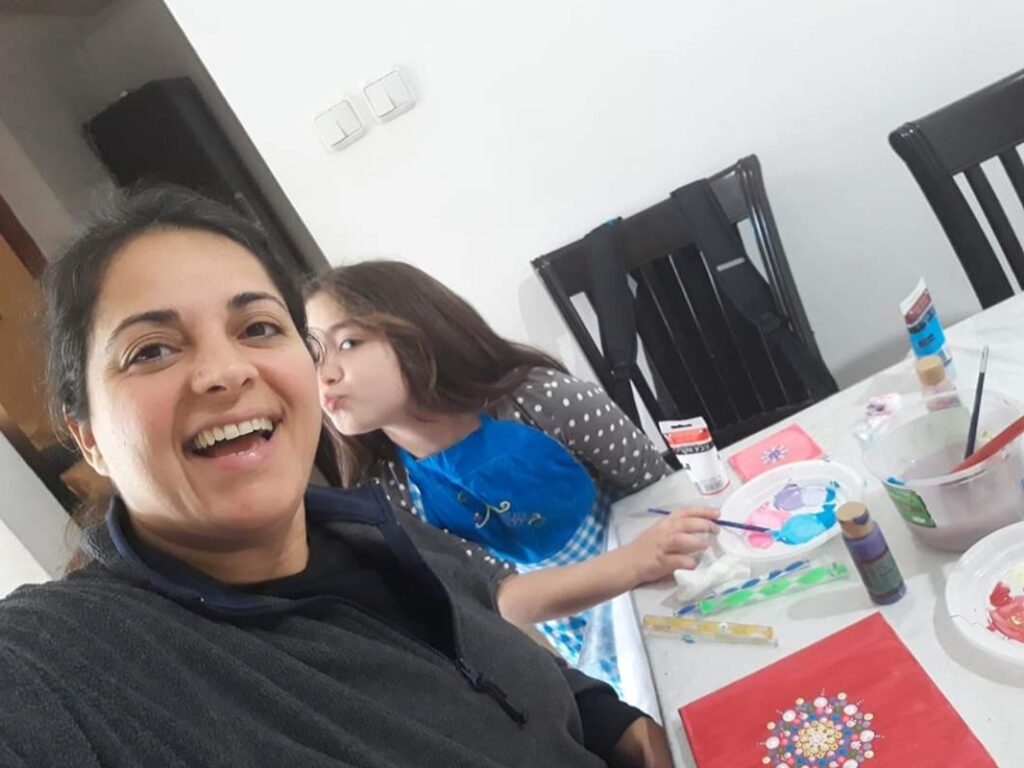 אישה וילדה מציירות יחד ליד שולחן עם צבעים